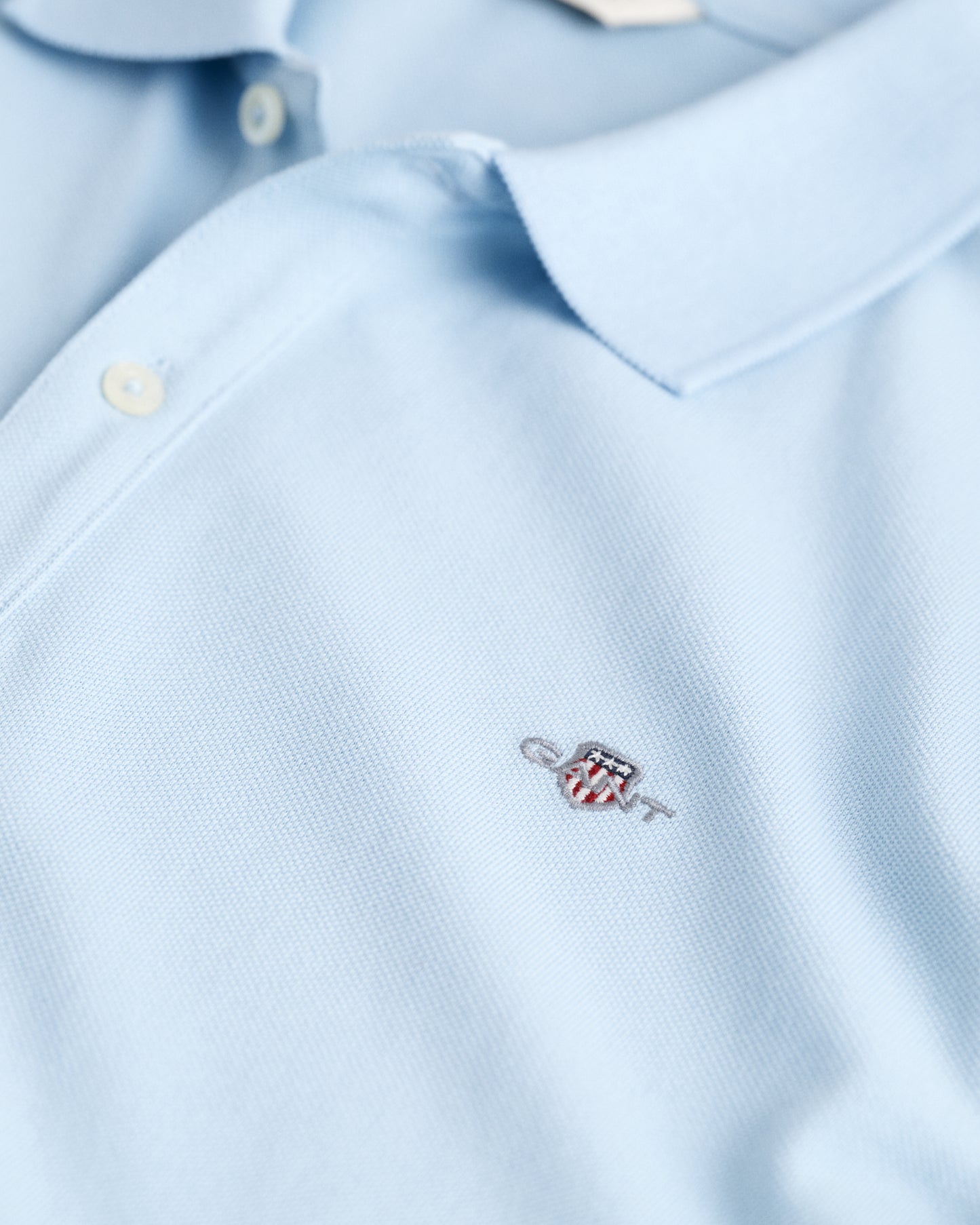 CALMING BLUE, SHIELD SS PIQUE, CLOSE-UP BY GANT AU.