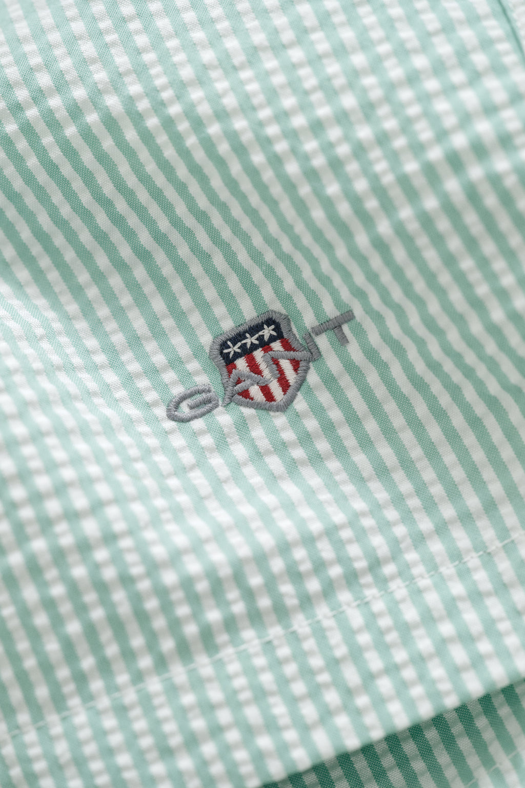 MUTED TURQUOISE, STRIPED SEERSUCKER SWIM SHORTS, FLAT-LAY BY GANT AU.