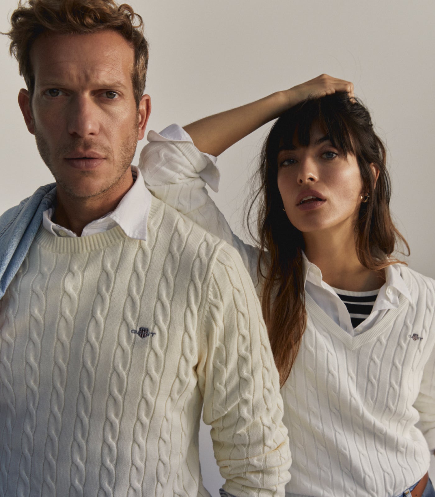 Two people wearing white GANT cable knit sweaters against a neutral background