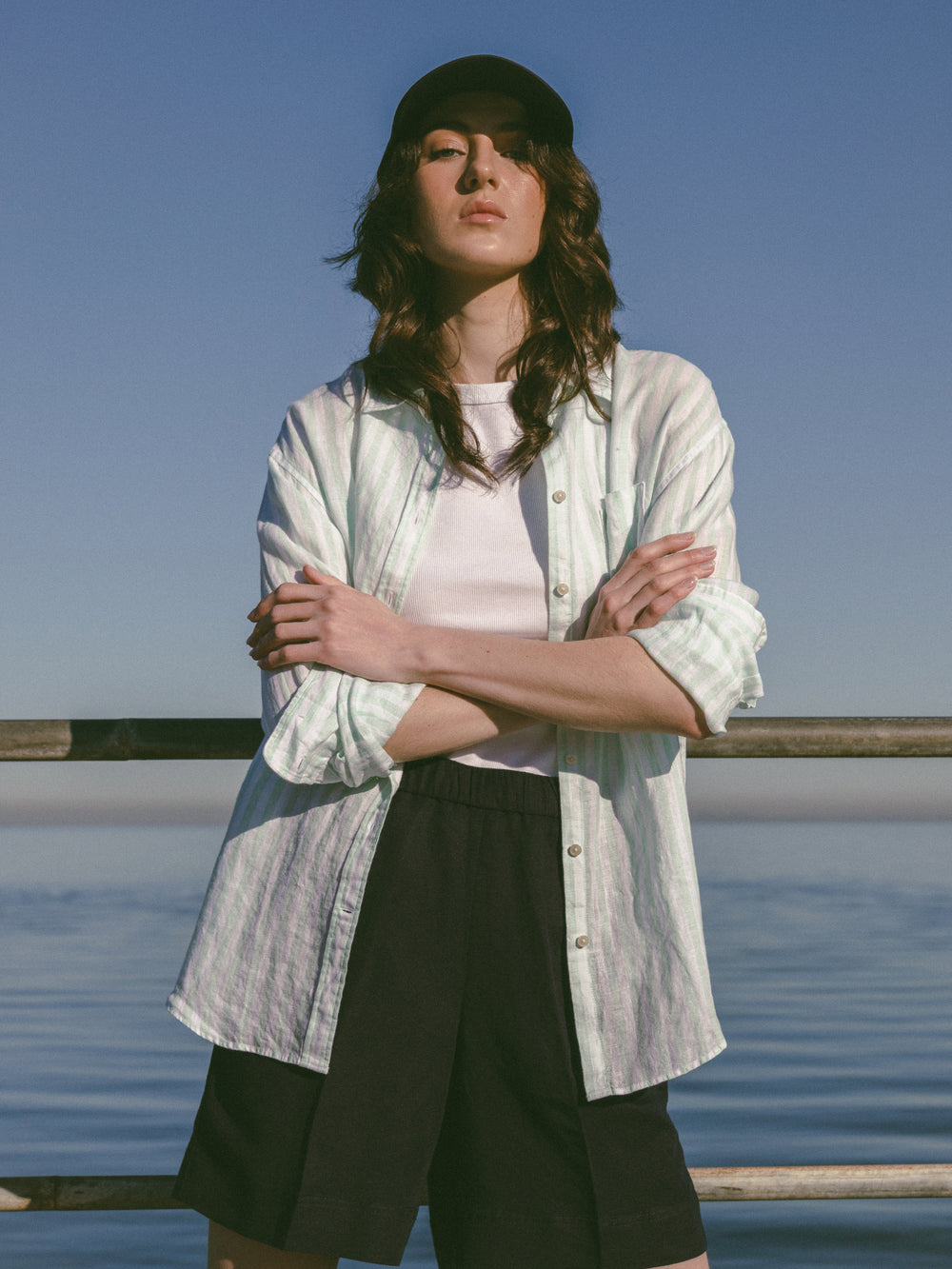 Woman standing by the water wearing the GANT Relaxed Fit Striped Linen Shirt.