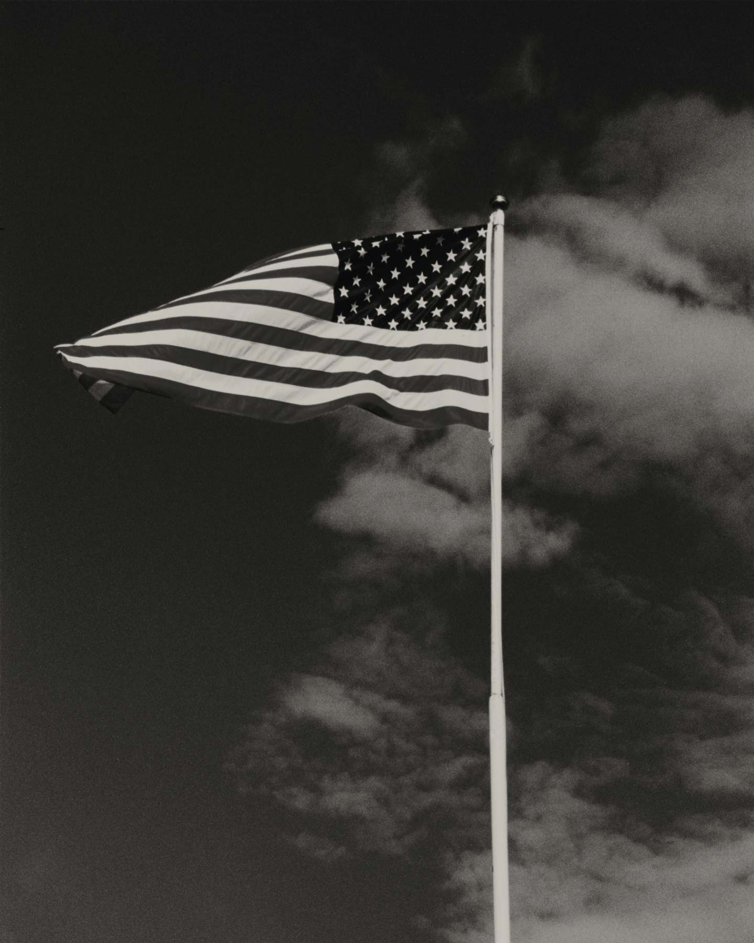 American flag against a dark, cloud-filled sky